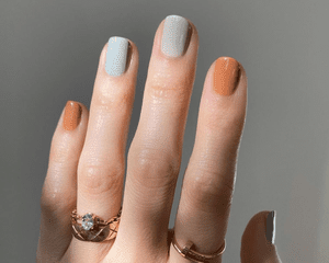 hand with blue, orange, and light green manicure